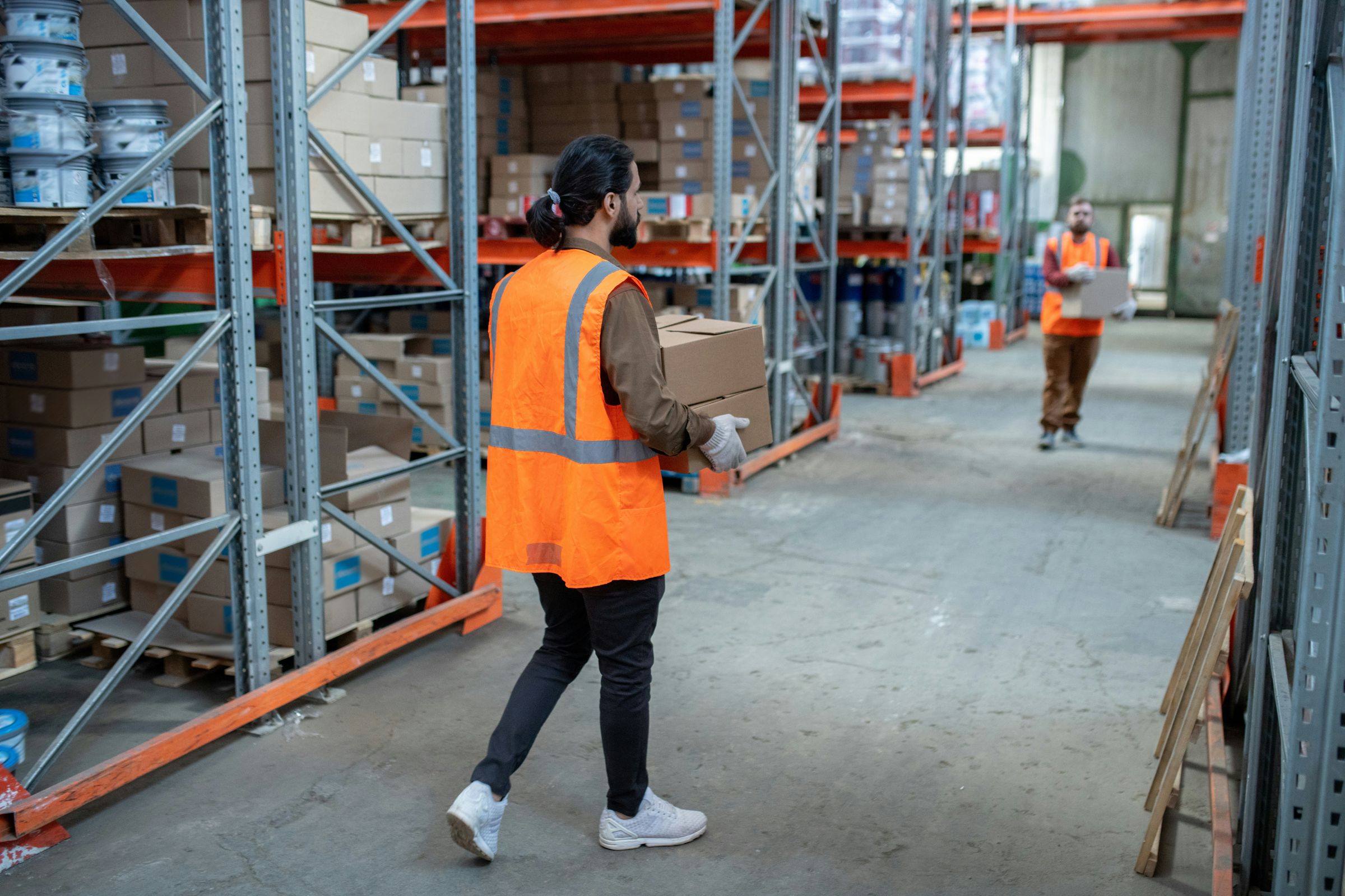 Un operador de almacén lleva cajas por el pasillo entre los racks